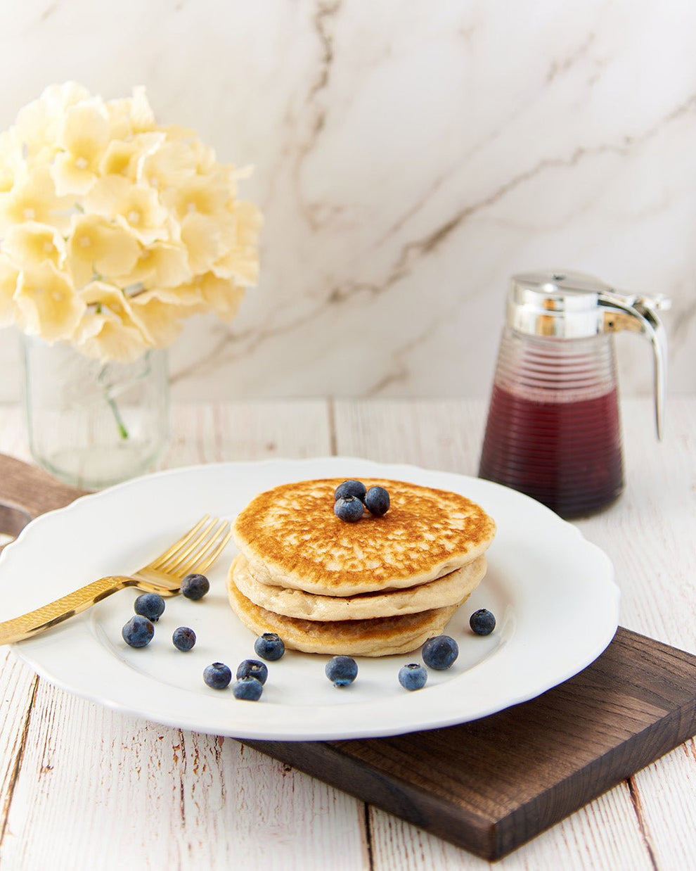 Pancakes with blueberries and syrup on white plate